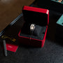 A Cartier Tonneau Platinum wristwatch in a red box, accompanied by a card, tag, and extra strap on a dark surface.