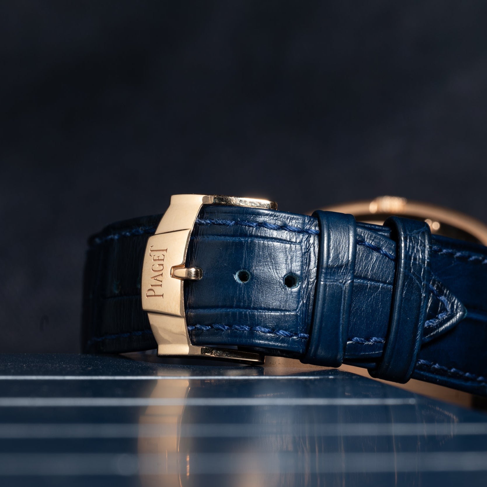 Close-up of the Piaget Black Tie Andy Warhol blue leather watch strap with a gold clasp, set against a dark background.
