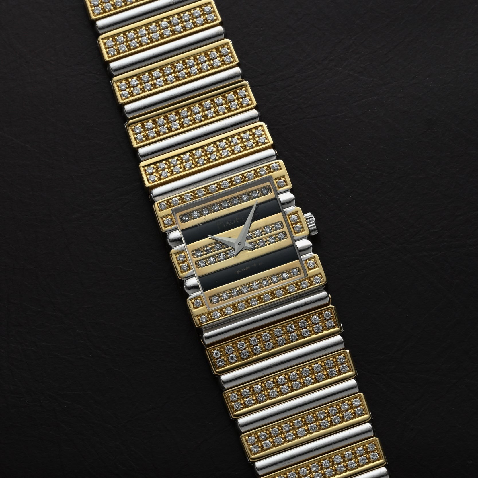 The Piaget Polo Pave wristwatch features rows of sparkling diamonds in gold and silver on a black textured background.