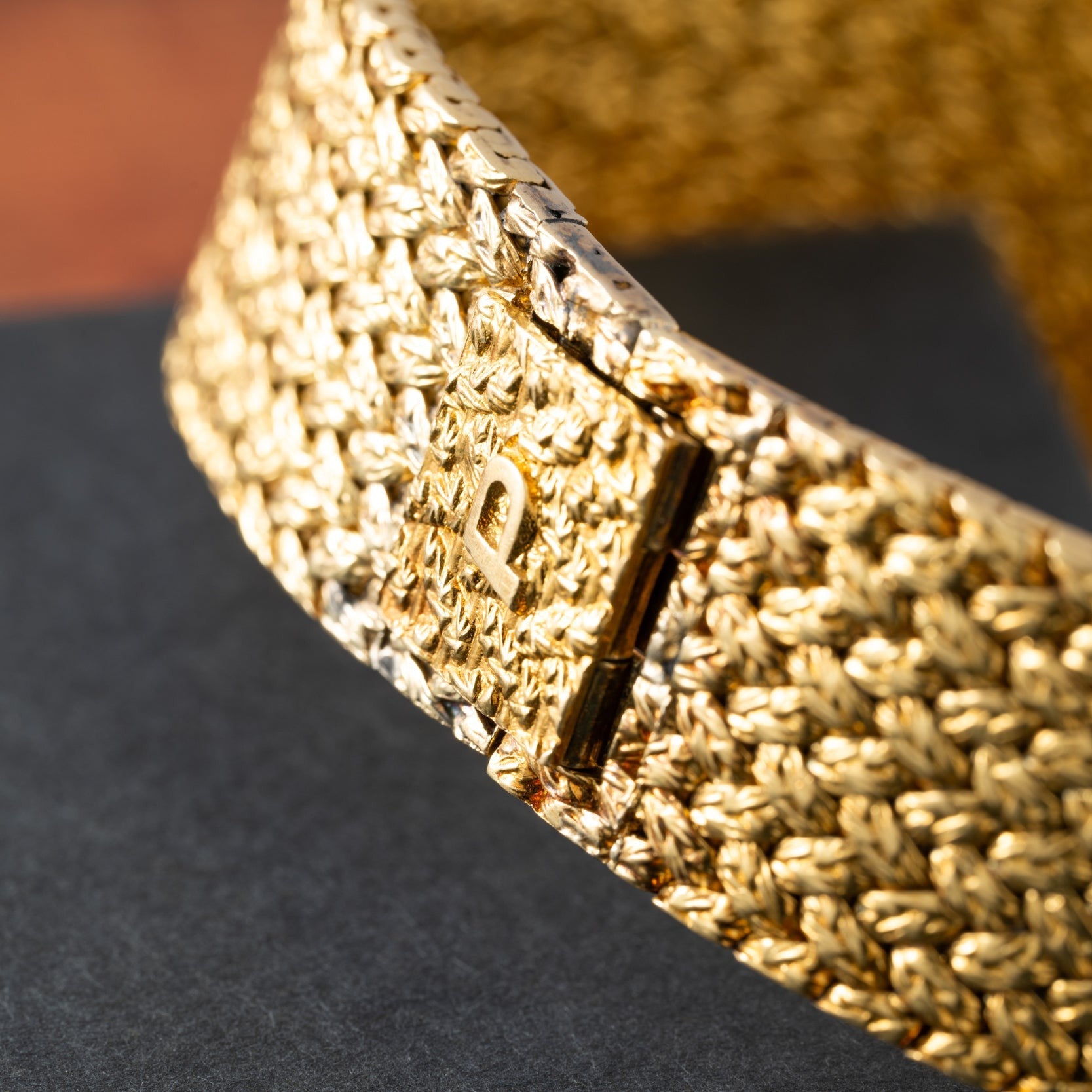 Close-up of the Piaget Pave Lapis Lazuli Dress Watch, showcasing a textured gold bracelet and a rectangular clasp adorned with a raised letter P.