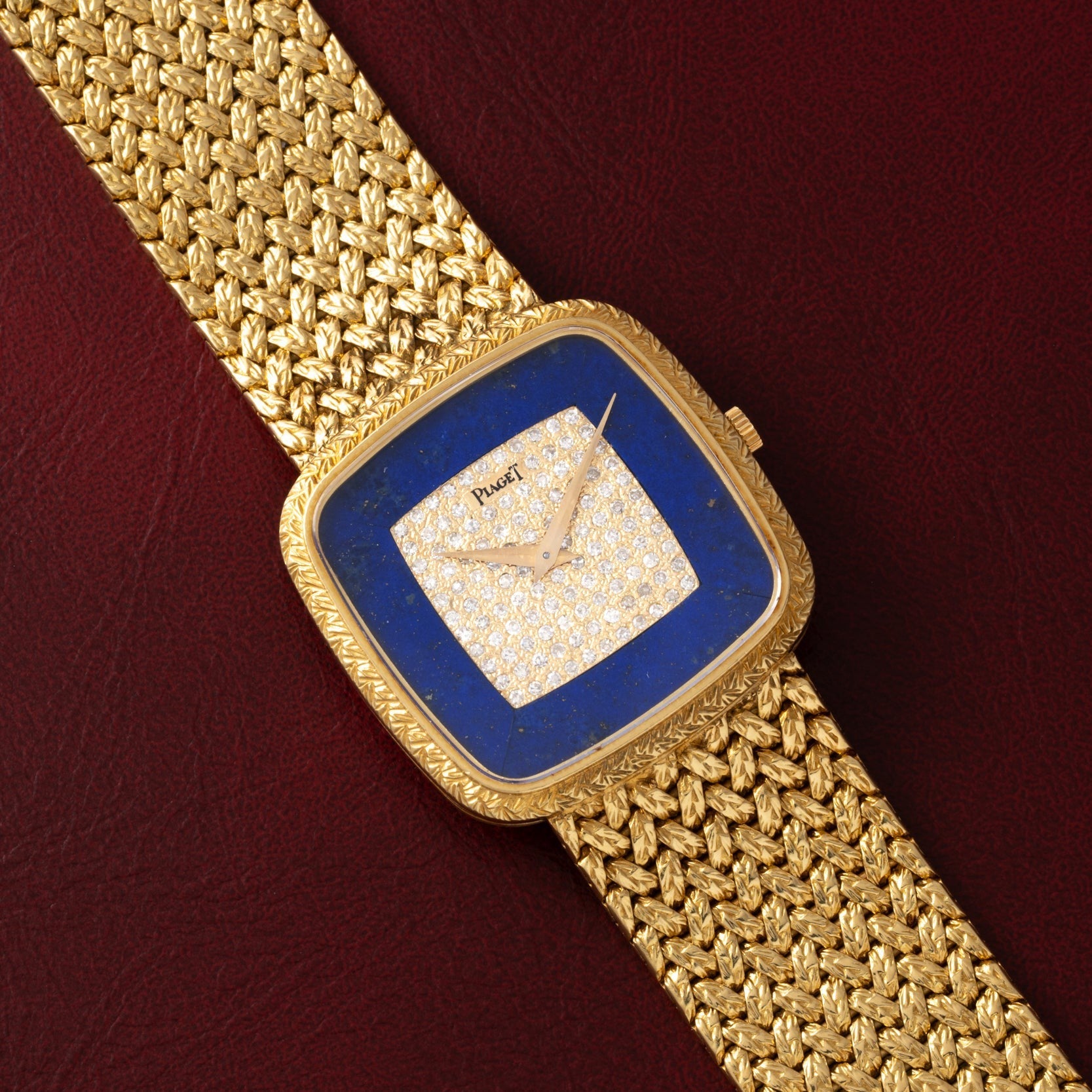 Piaget Pave Lapis Lazuli Dress Watch with a diamond-set face and blue border, displayed on a textured burgundy surface.
