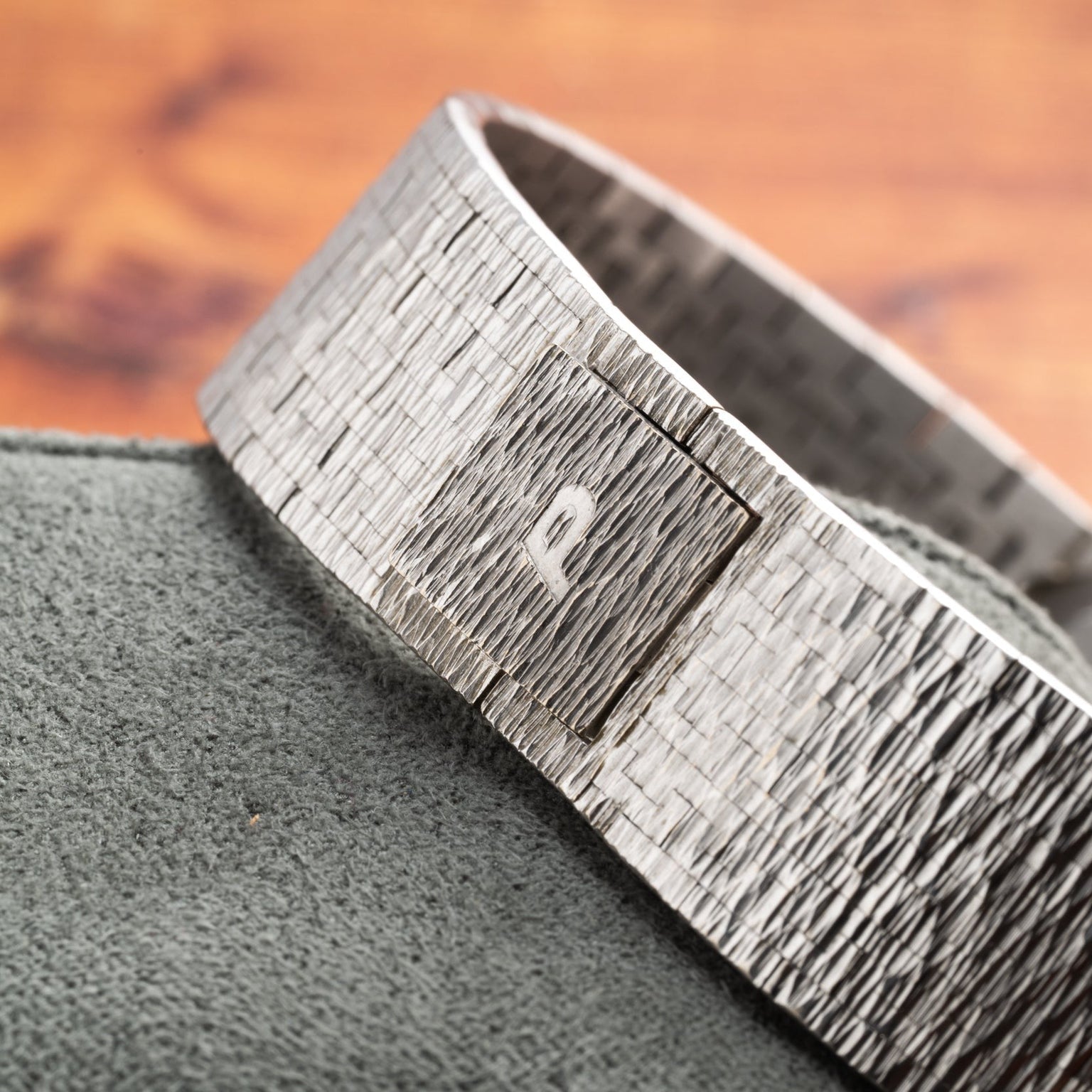 The Piaget Opal White Gold Dress Watch featuring a square detail is displayed on a soft green fabric surface.