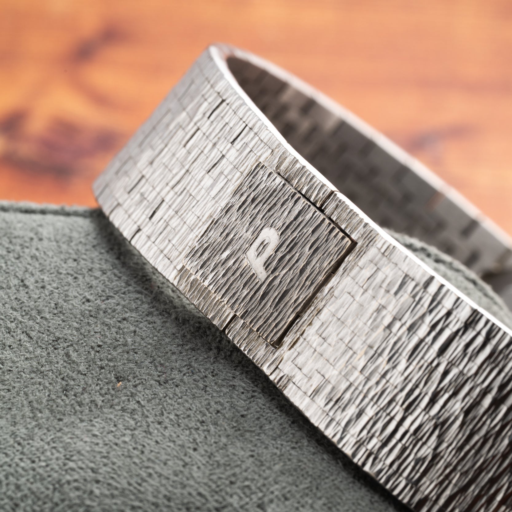 The Piaget Opal White Gold Dress Watch featuring a square detail is displayed on a soft green fabric surface.