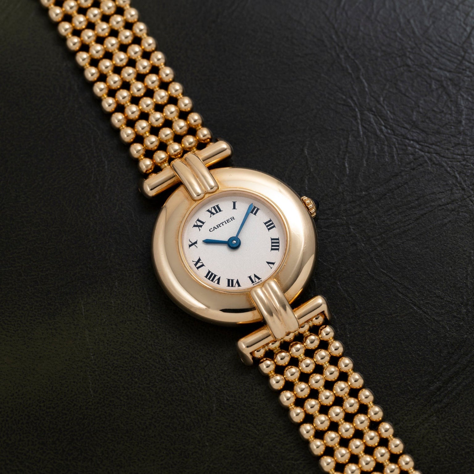 The Cartier Ladies Dress Watch features a gold case with Roman numerals on a black leather strap.