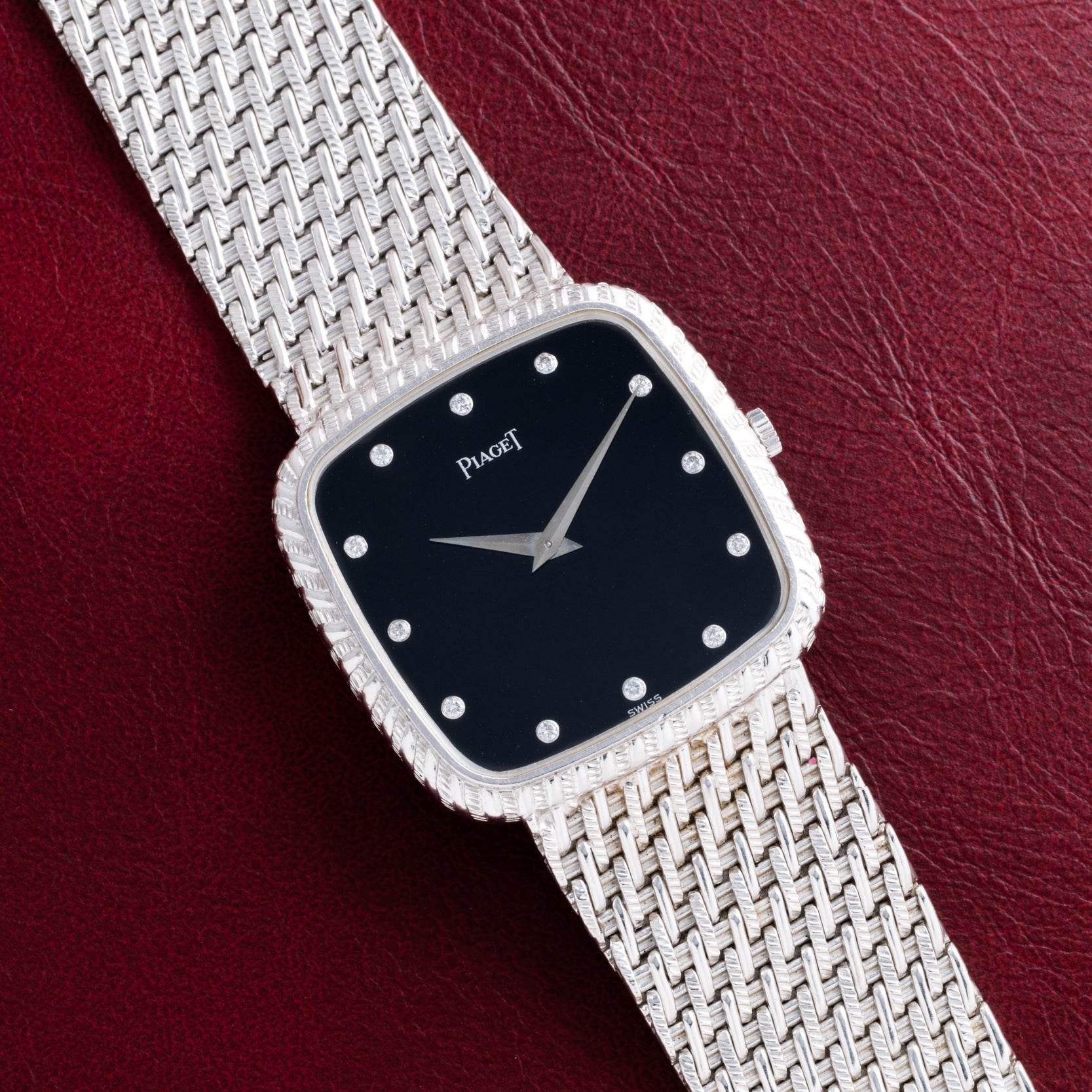 A Piaget Onyx Dial White Gold Dress Watch displayed against a red leather background.