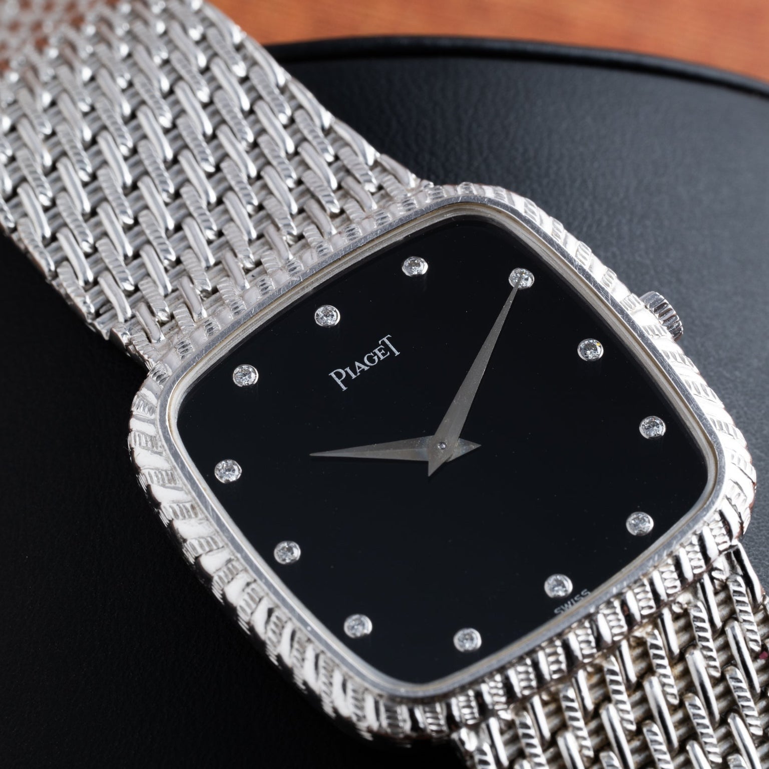 Piaget Onyx Dial White Gold Dress Watch featuring a sleek black face and diamond hour markers, set on a textured white gold band.