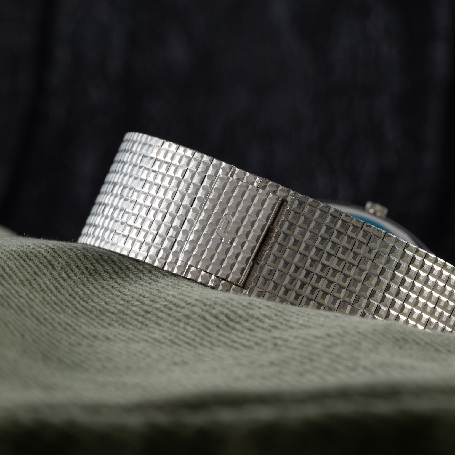 Close-up of the Piaget Sqound White Gold Dress Watch band displayed on textured green fabric.