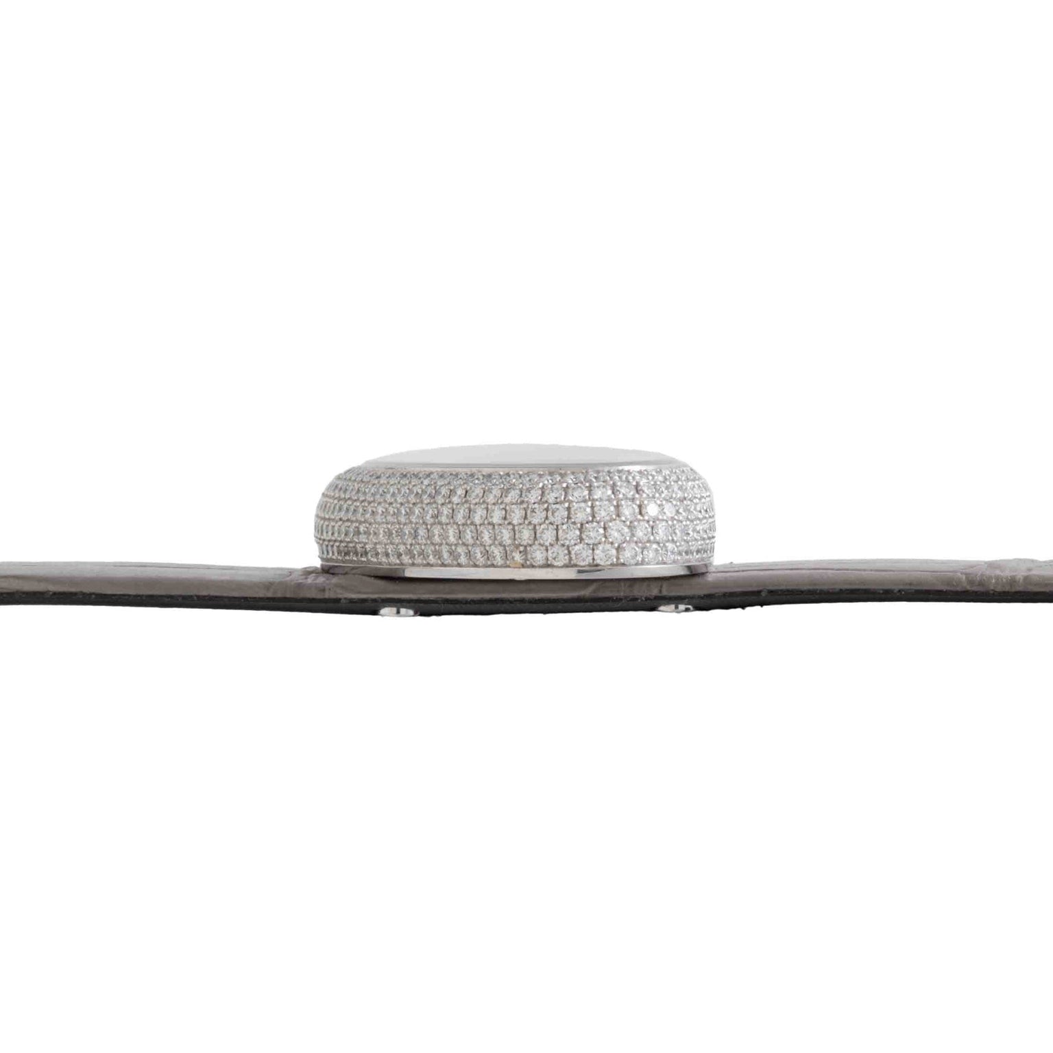 Side view of Cartier’s Libre Hypnose, a round silver object encrusted with diamonds, placed on a flat dark surface against a white background.