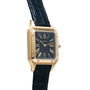 The Cartier Santos Dumont wristwatch features a square black face with Roman numerals and a black leather strap.