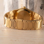 Close-up of the gold metal band and clasp of a Vacheron Constantin 222 luxury wristwatch on a light wooden surface.