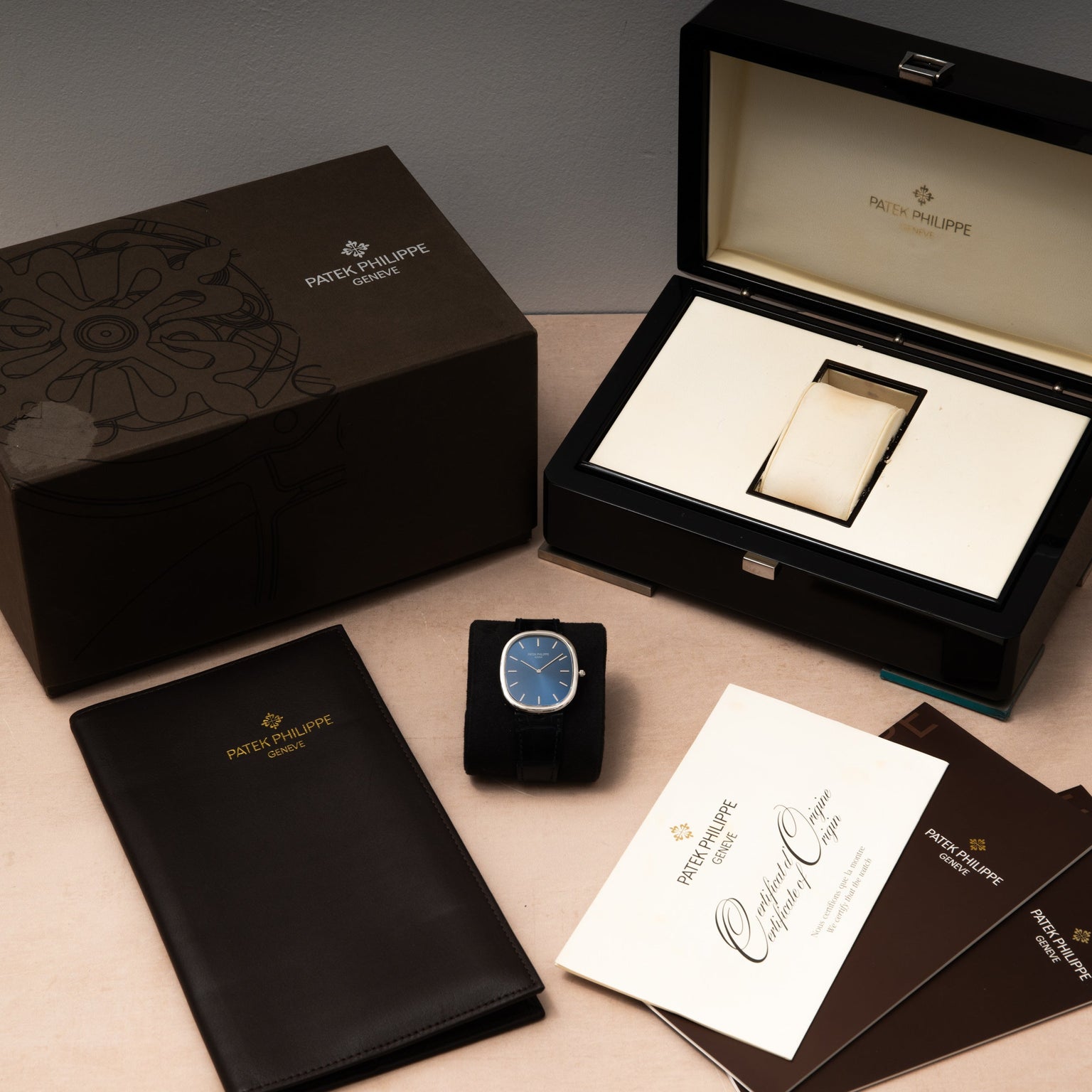 A Patek Philippe Ellipse Jumbo watch with its box, case, certificate, and documents neatly arranged on a table.
