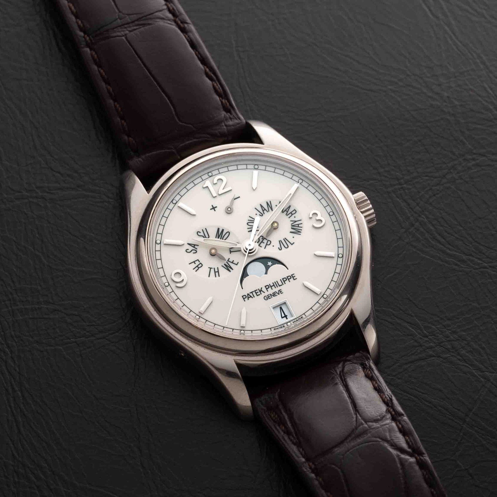 Patek Philippe Annual Calendar Moonphase watch with brown leather strap displayed on black leather.