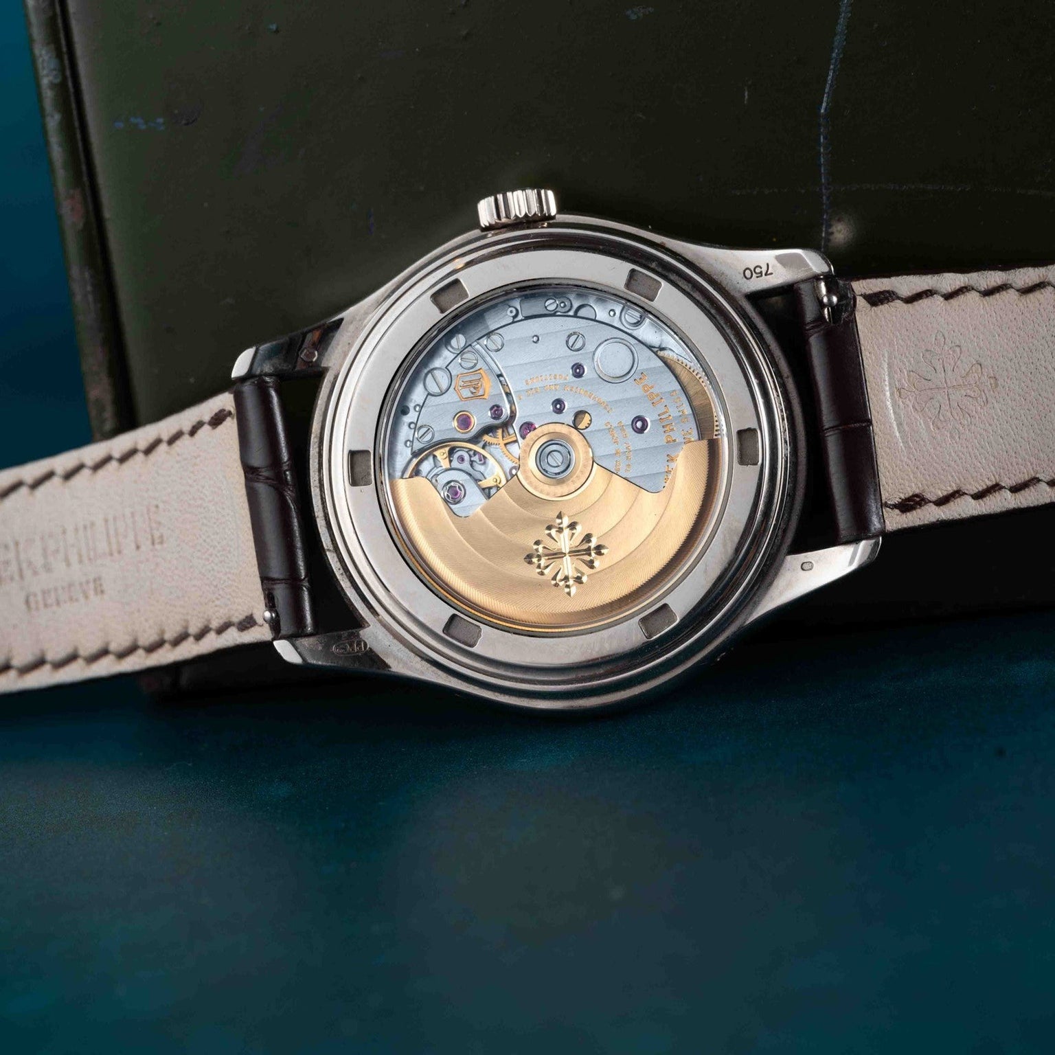 The back of the Patek Philippe Annual Calendar Moonphase wristwatch displays its exposed mechanical movement and a brown leather strap.