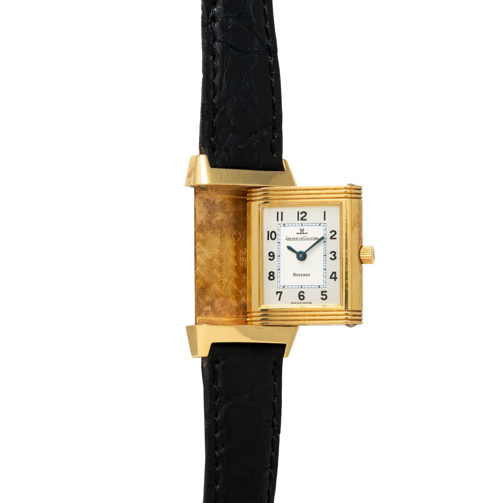 The Jaeger-LeCoultre Reverso Classique, by Jaeger-LeCoultre, features a gold rectangular case, white dial, and black leather strap, shown partially rotated to display its side.