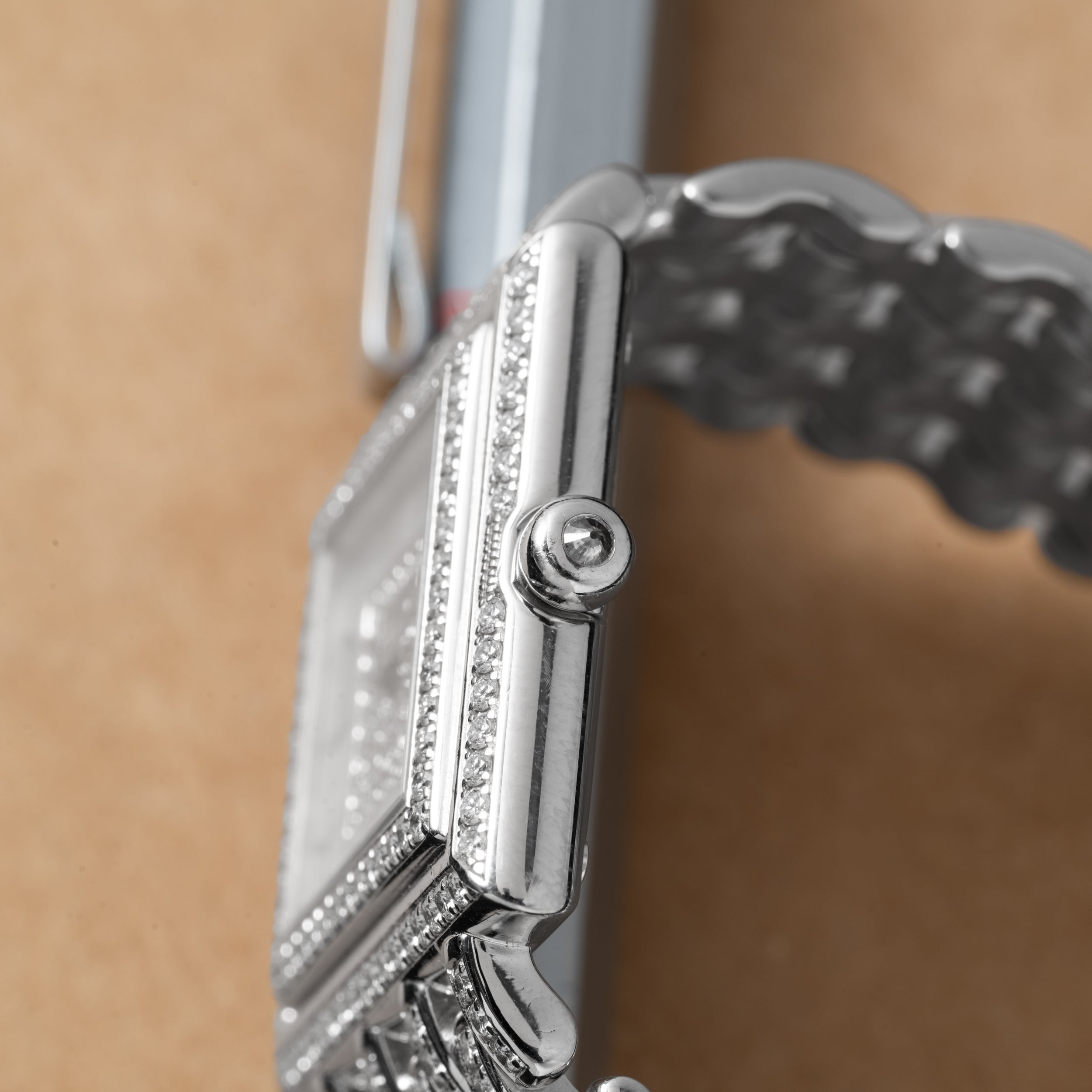 Close-up of the Patek Philippe Gondolo silver wristwatch with a metal band and diamond accents, displayed on a brown surface.