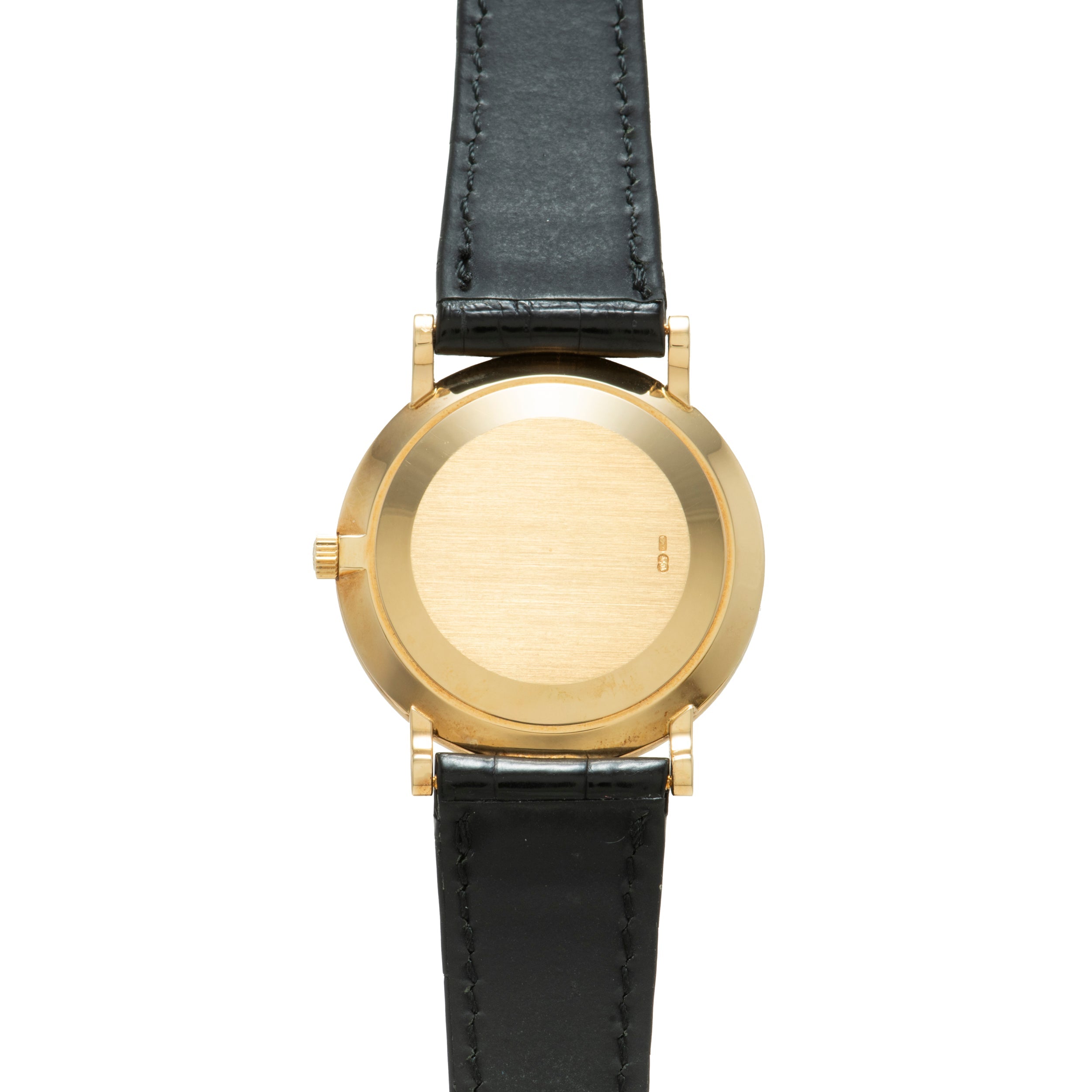 The Patek Philippe Calatrava wristwatch features a blank face and black leather strap, displayed from above on a white background.