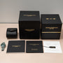 A Girard-Perregaux Laureato Green Ceramic Aston Martin Edition watch with its box, warranty card, booklet, and certificate on a table.