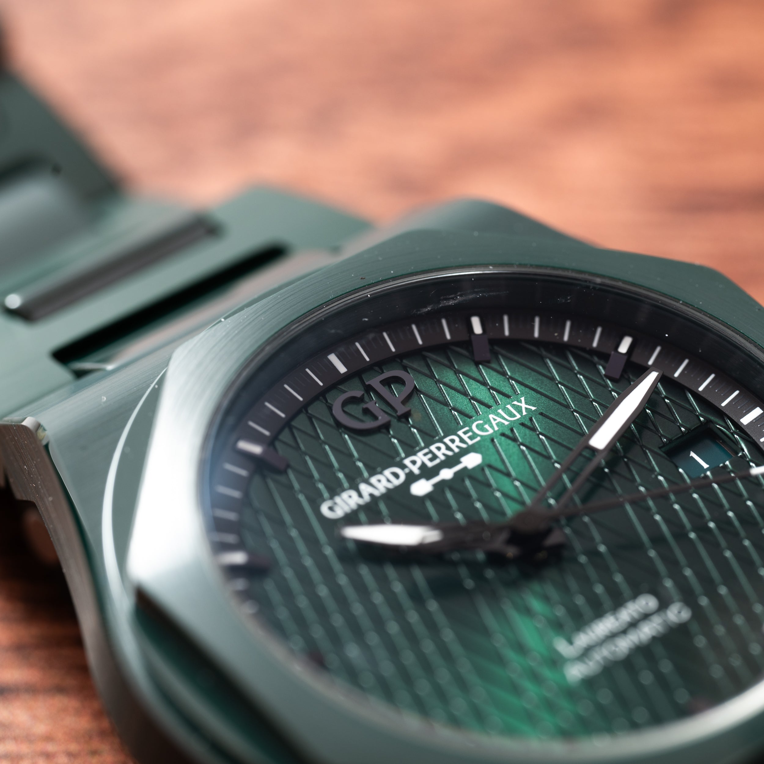 Close-up of the Laureato Green Ceramic Aston Martin Edition by Girard-Perregaux, highlighting its green dial and hands on a wooden surface.