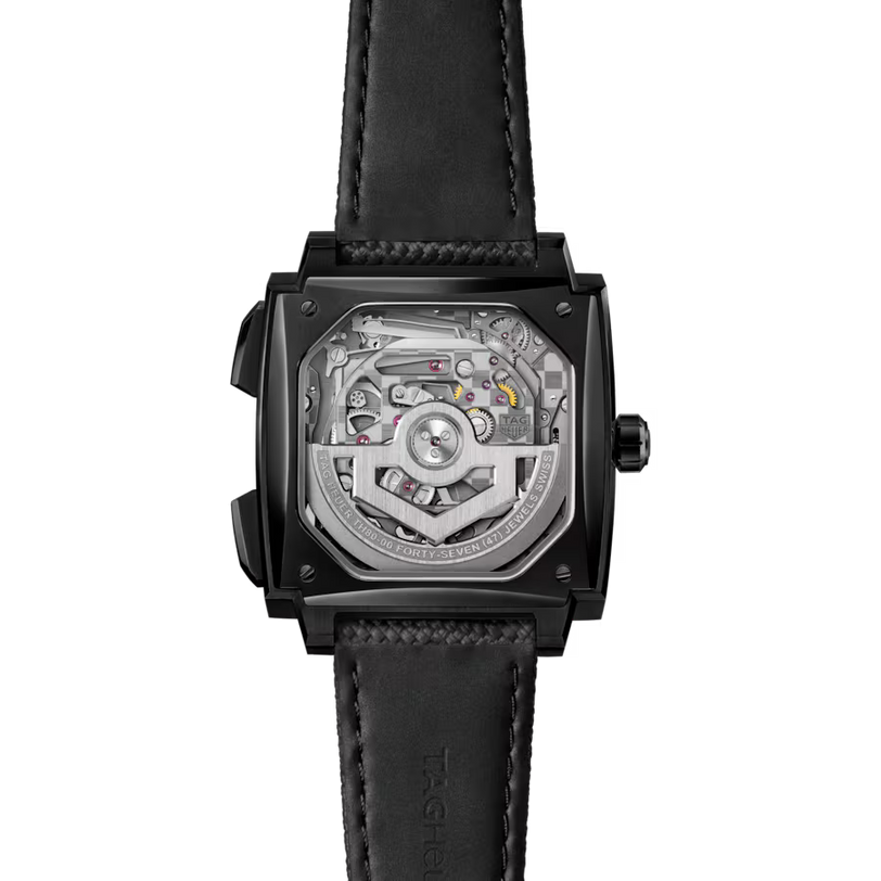 Square black watch with visible mechanical movement through crystal caseback and black leather strap.