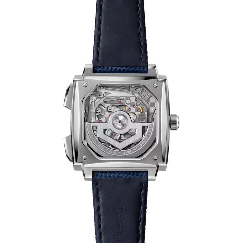 Square stainless steel watch with exposed mechanical movement visible through clear case back, dark blue leather strap.