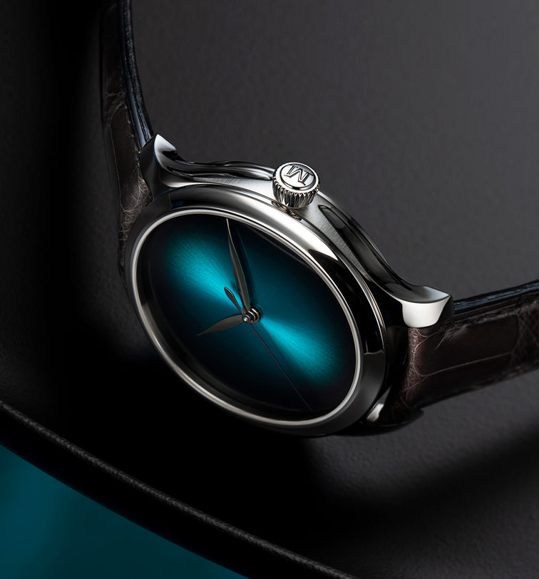 Silver-cased watch with blue lagoon dial, dark leather strap, and crown detail on polished steel case.