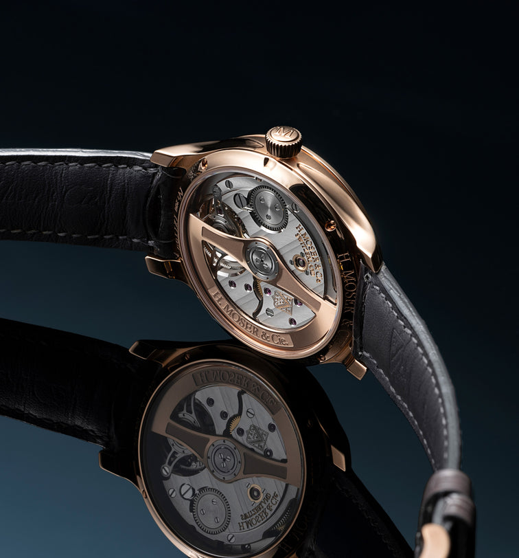 Rose gold tourbillon watch with black leather strap and visible mechanical movement through transparent case back.