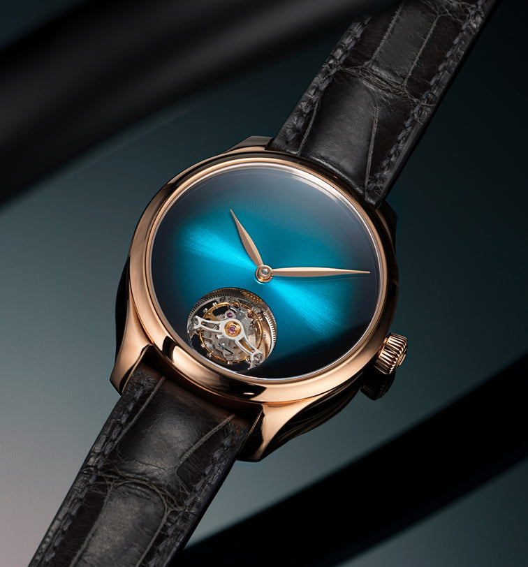 Rose gold watch with blue gradient dial, visible tourbillon at 6 o'clock, rose gold hands, and black crocodile leather strap.