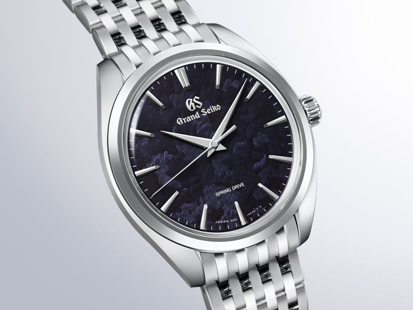 Grand Seiko watch with silver stainless steel bracelet, dark blue dial, and applied hour markers.
