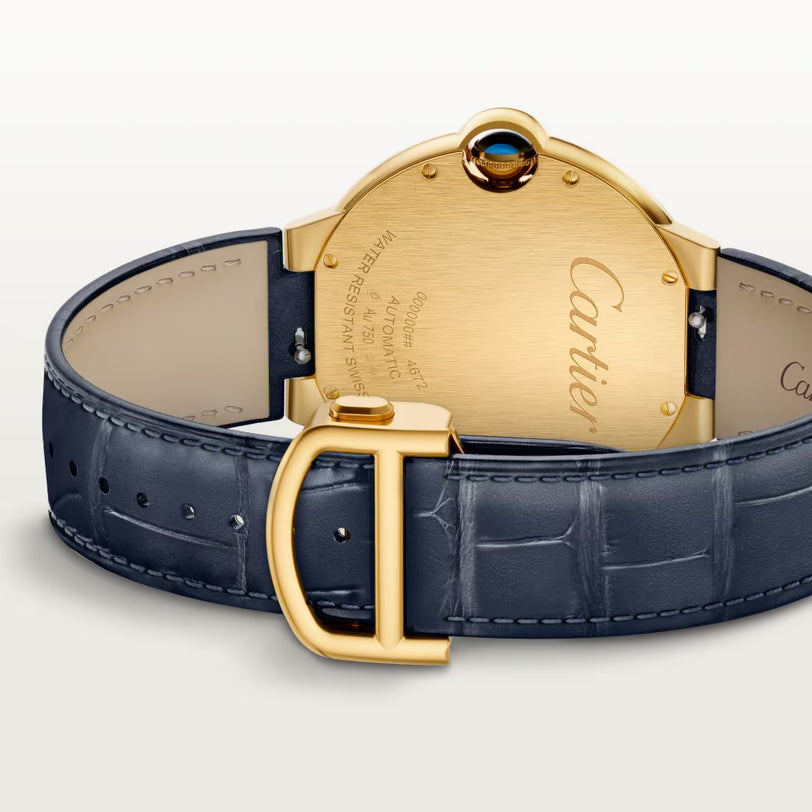 A close-up of the Ballon Bleu De Cartier Watch by Cartier, showing its gold case, blue cabochon crown, blue leather strap with gold “C”-shaped buckle, and engraved metal back details.