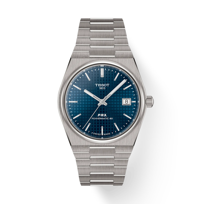The Tissot PRX 38 is a stainless steel automatic watch featuring a blue textured dial, silver markers, date at 3 o’clock, 80-hour power reserve, and a silver link bracelet displayed on a white background.