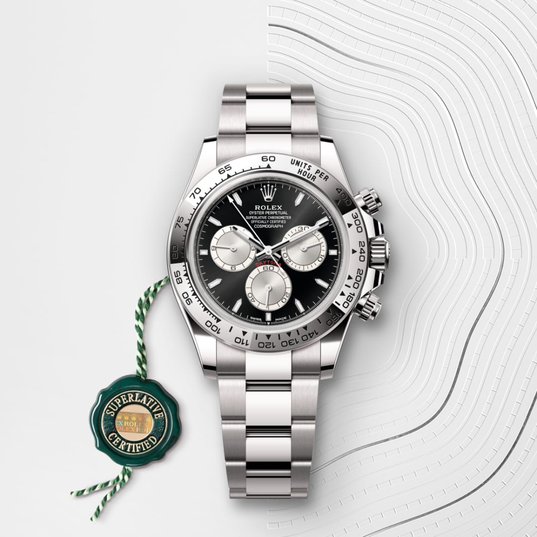 A stainless steel Rolex Daytona watch with a black dial and three subdials, shown on a white textured background.