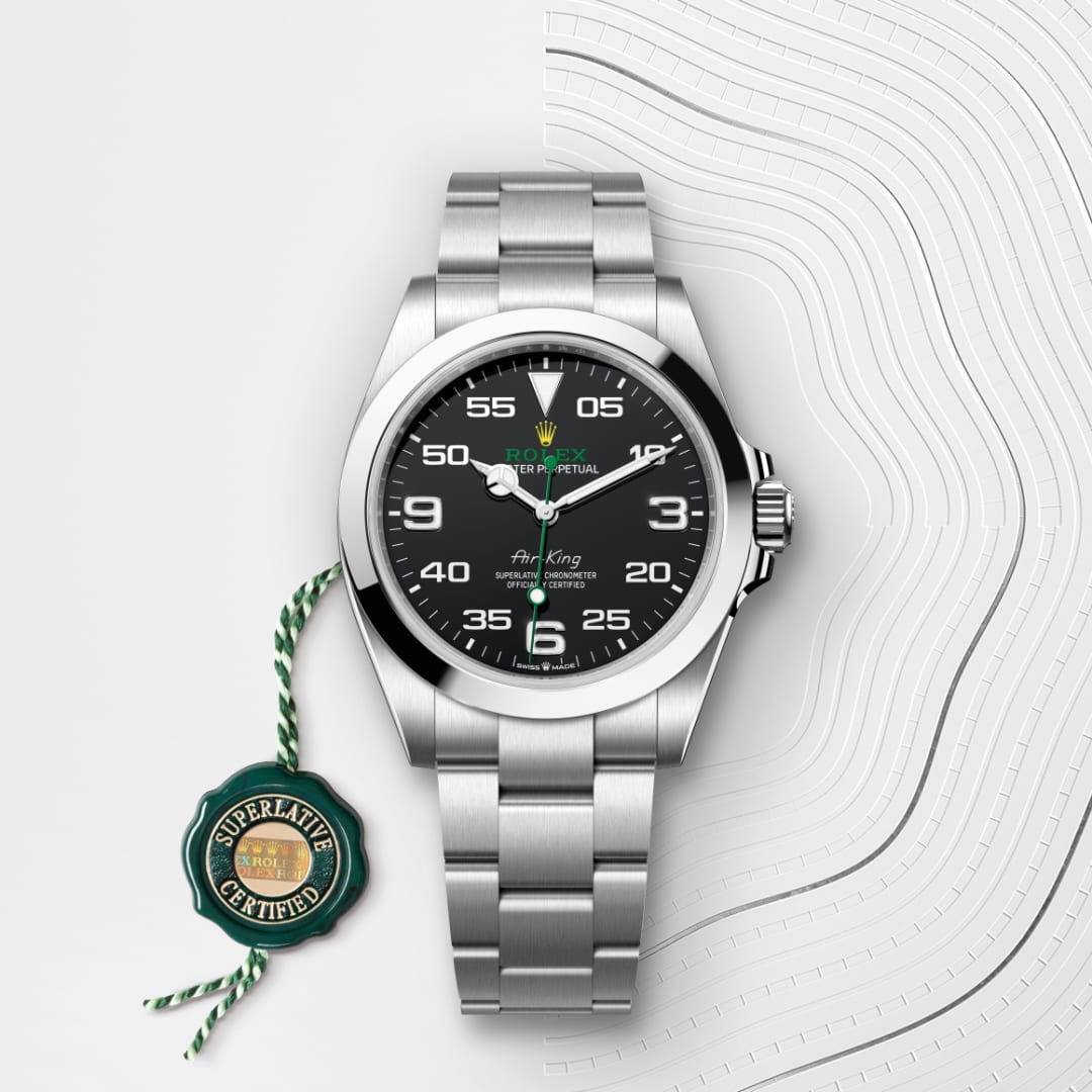 A silver Rolex Oyster Perpetual Air-King watch with a black dial and certification tag on a textured white background.