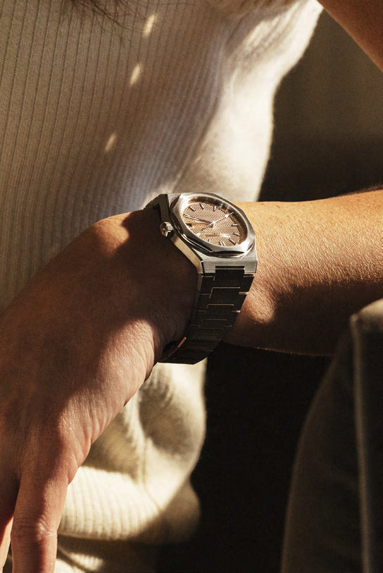 Close-up of a person's wrist wearing a silver watch with a blurred background