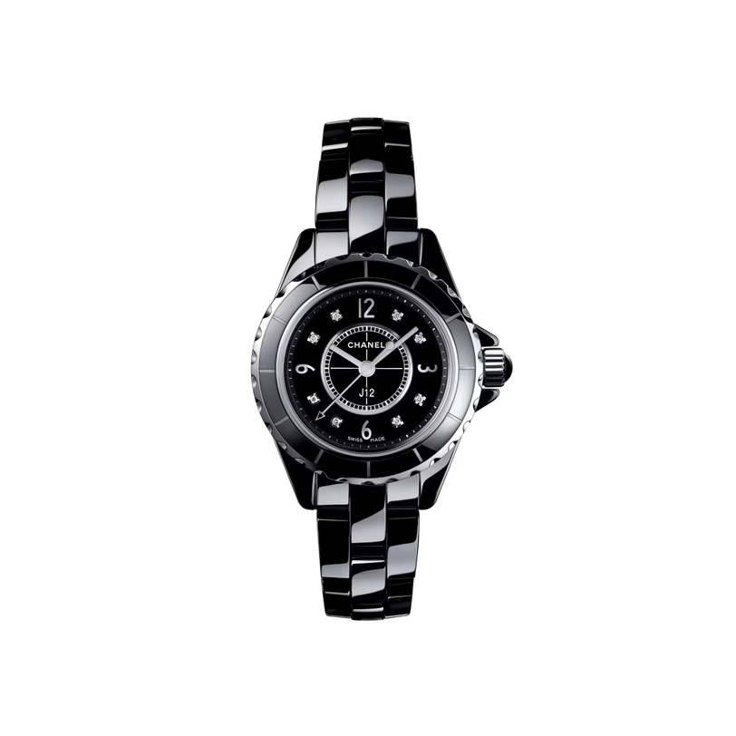 The Chanel J12 is a sleek black wristwatch with a round face, diamond indicators, silver details, and a durable ceramic-steel link bracelet, shown on a plain white background.