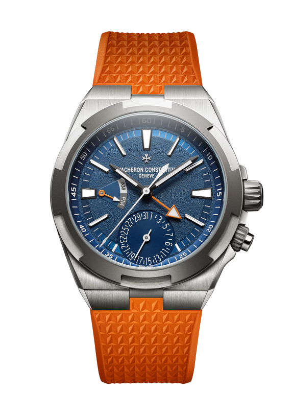 Stainless steel watch with blue dial, orange rubber strap, dual time zone subdial, and orange triangle hand indicator.