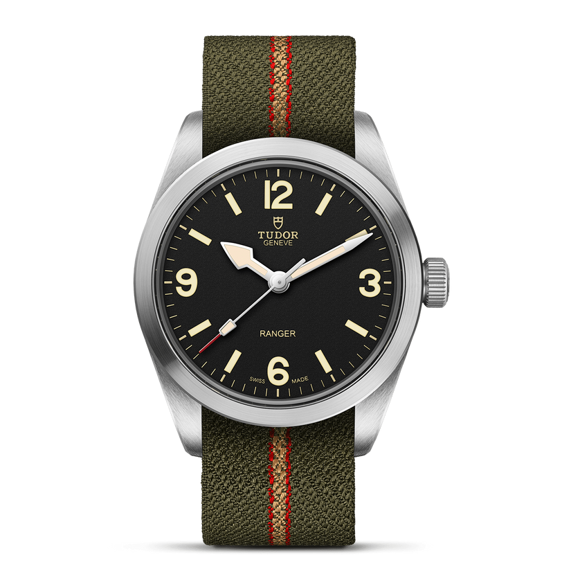 The TUDOR Ranger is an expedition watch with a black dial, large cream numerals and hands, a stainless steel case, and an olive-green fabric strap with a red center stripe.