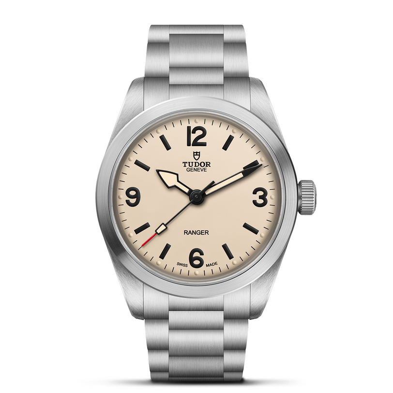 The TUDOR Ranger is an expedition watch featuring a stainless steel case and bracelet, cream dial, black hour markers and hands, large numerals at 3, 6, 9, and 12, plus a bold red-tipped seconds hand.
