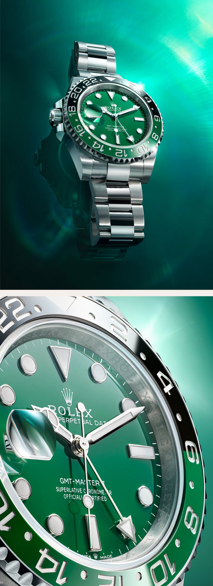 A close-up of a green Rolex GMT-Master II watch with a silver bracelet, glowing under teal light.