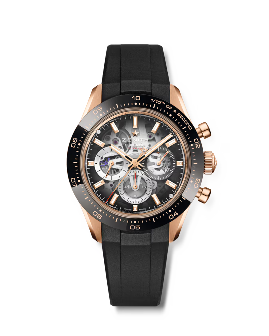 Rose gold chronograph watch with black dial, visible movement, black rubber strap, and tachymeter bezel.