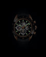 Chronograph watch with black dial, bronze case, luminous hour markers, and visible movement dial subdials.