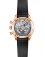 Rose gold chronograph watch with exposed movement visible through transparent caseback and black rubber strap.