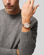 Man wearing two-tone silver and rose gold chronograph watch with white dial on wrist.