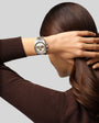 Person wearing a silver watch on a plain background
