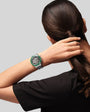 Sport watch with green bezel and metallic band worn on wrist.