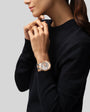 Woman wearing black sweater with rose gold and silver two-tone watch with chronograph dial on wrist.