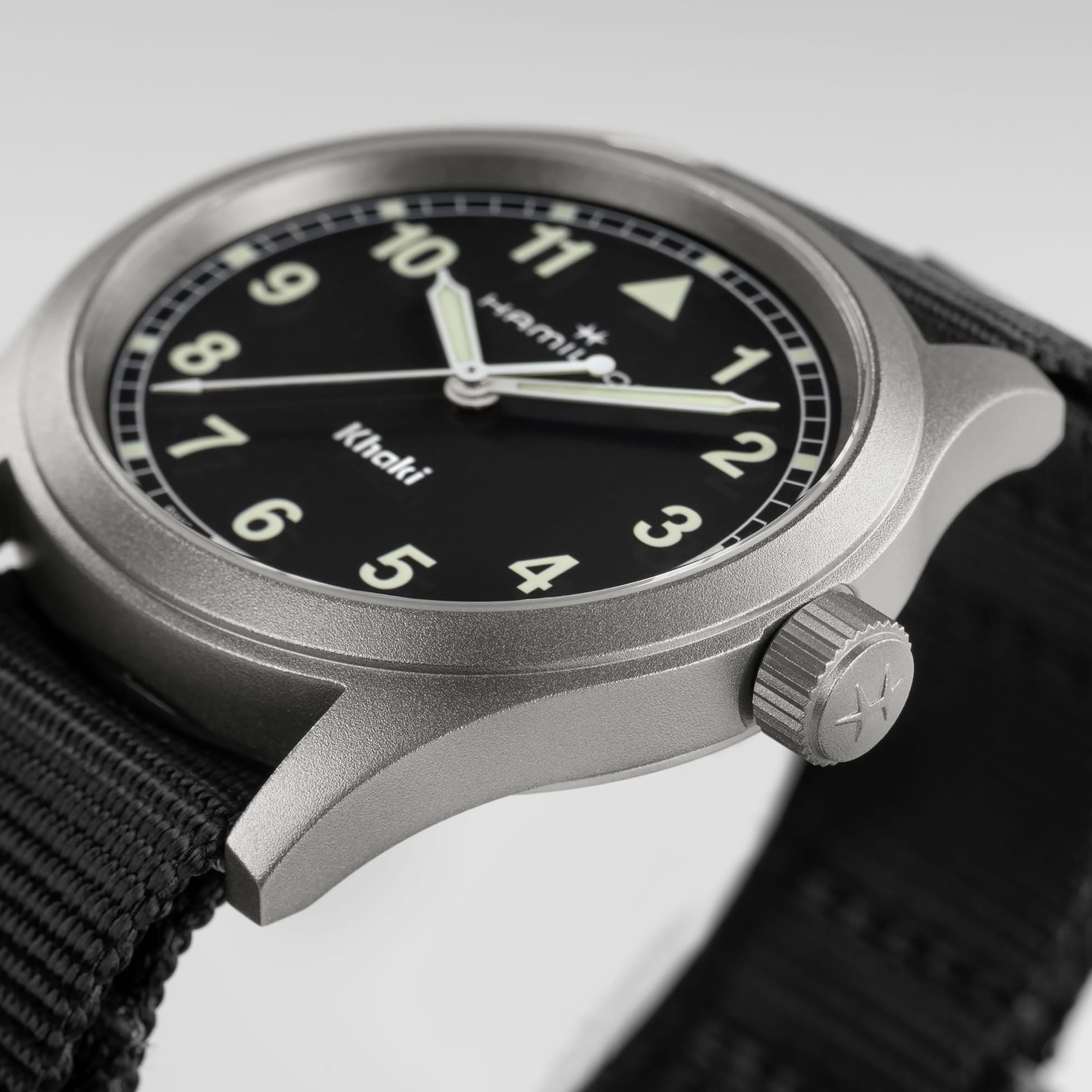 A close-up of the Hamilton Khaki Field Quartz wristwatch featuring a black face, white numbers, and a black fabric strap.