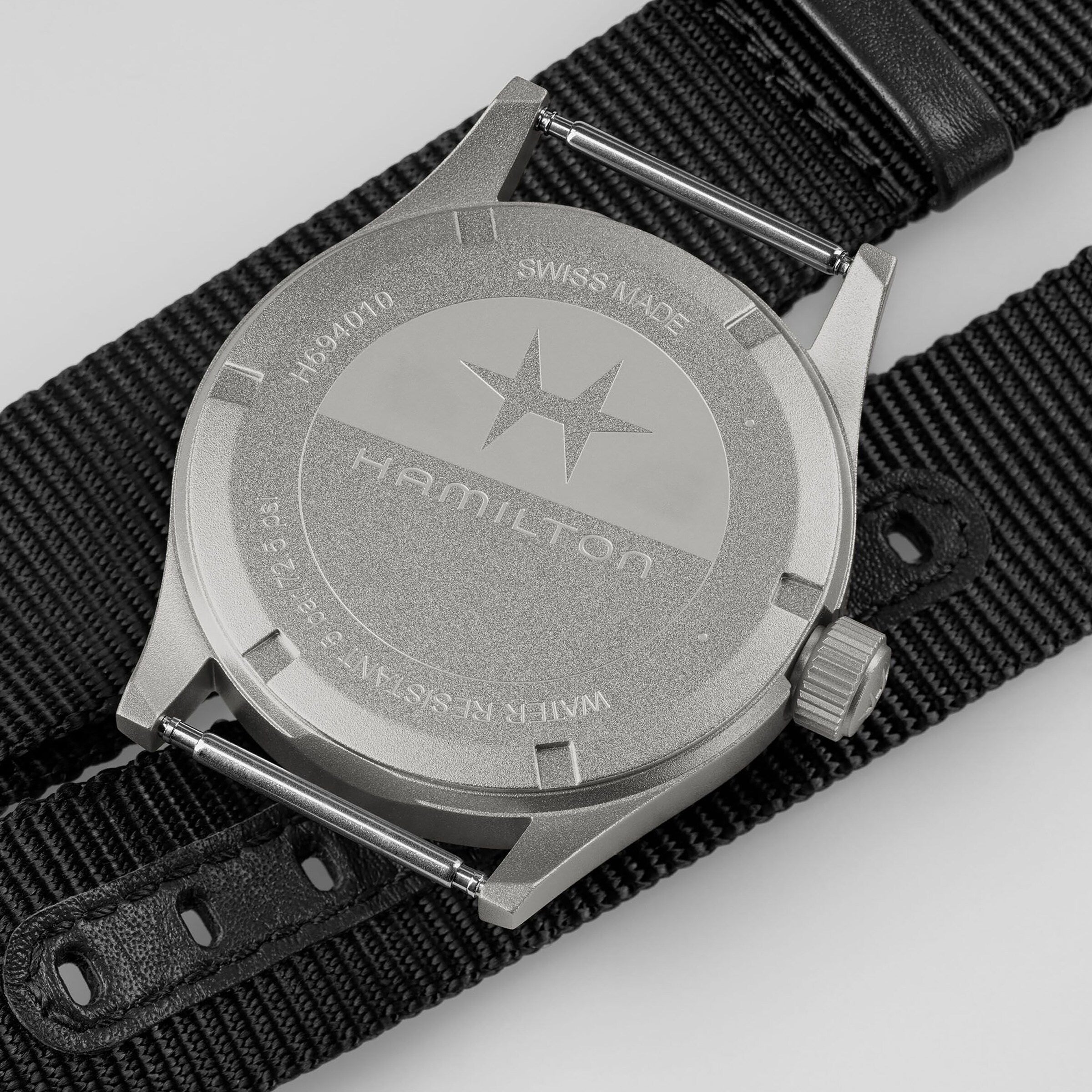Back of the Hamilton Khaki Field Quartz wristwatch featuring a star logo, serial number, and black fabric strap.