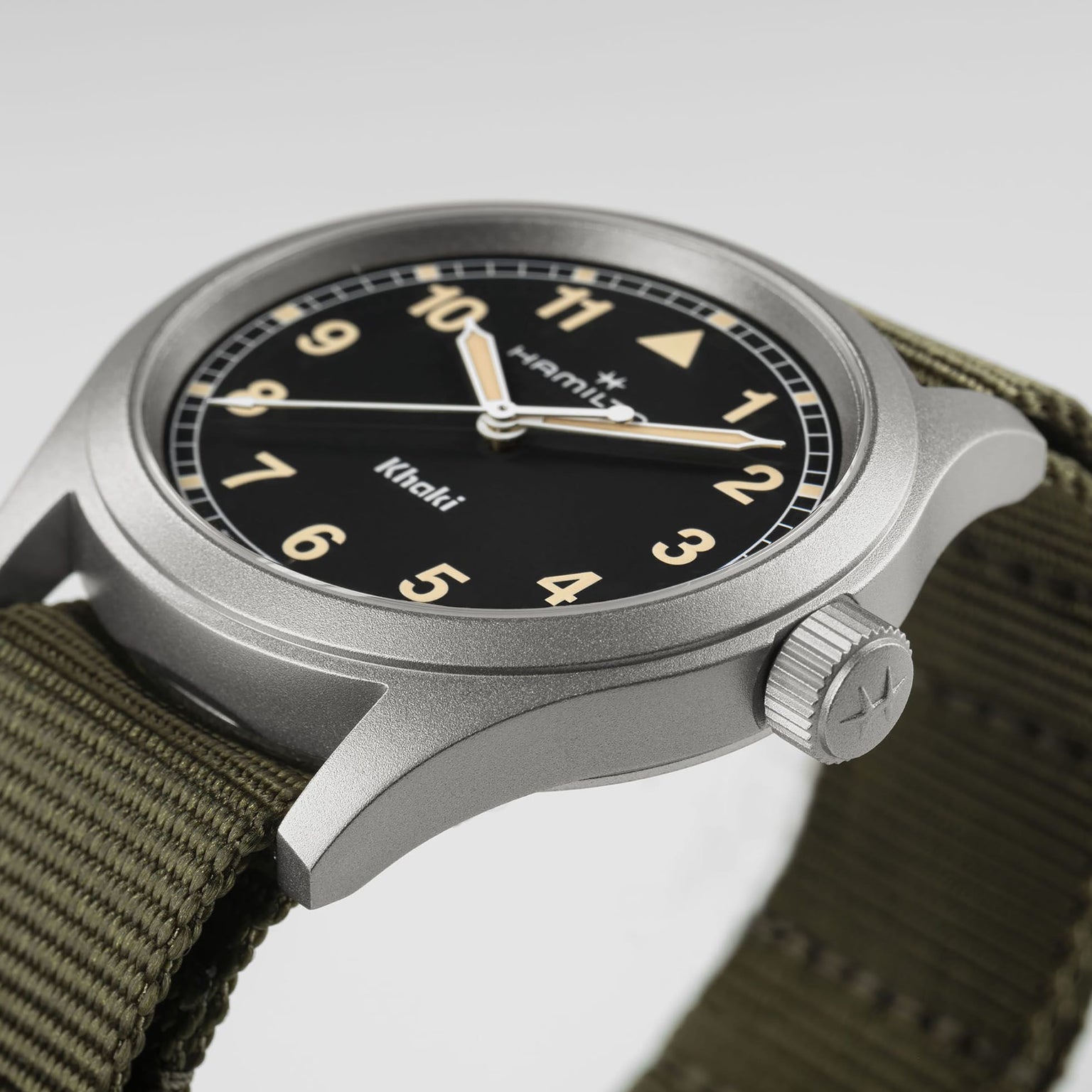 Close-up of a Hamilton Khaki Field Quartz watch featuring a black dial and an olive green fabric strap.