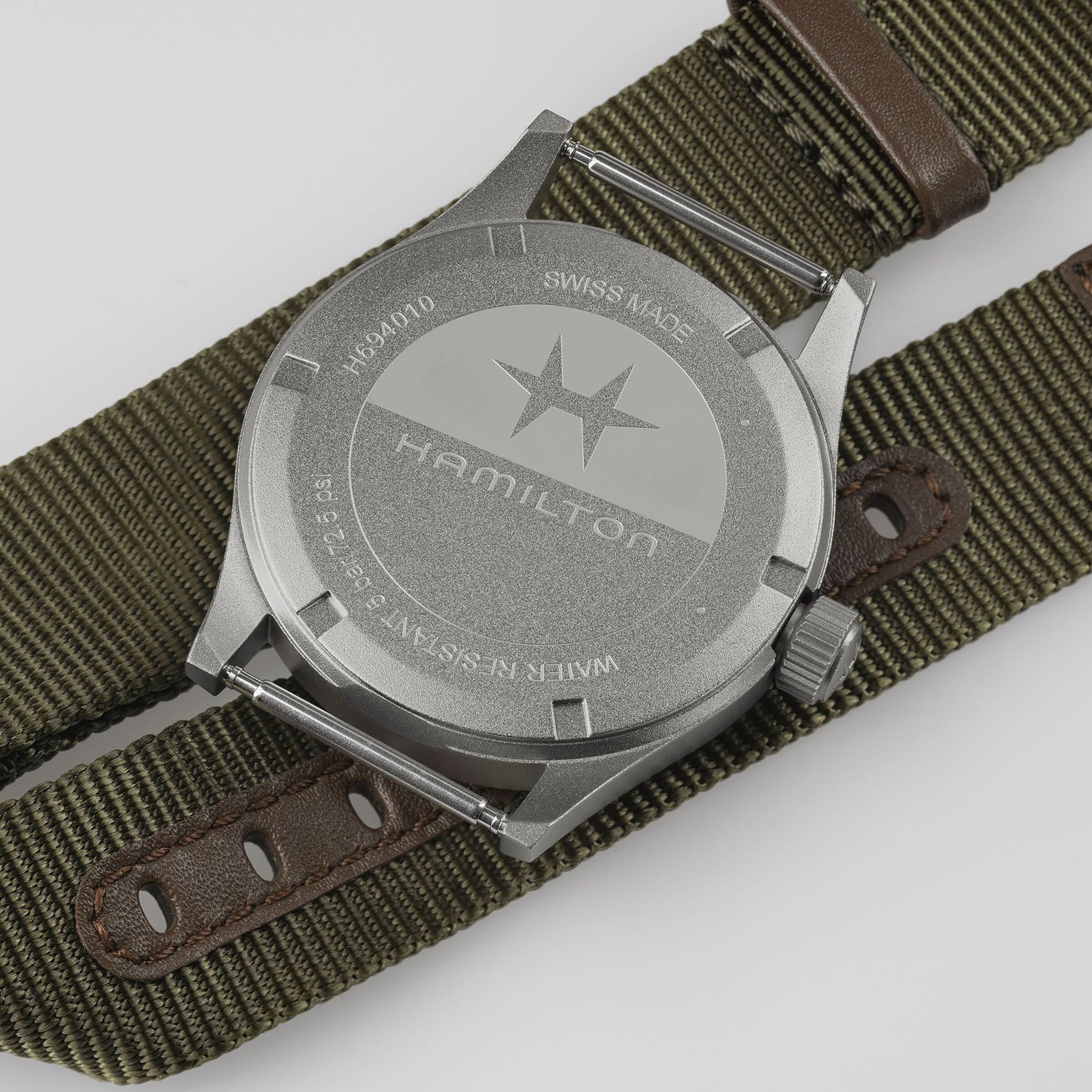 Back of a Hamilton Khaki Field Quartz watch featuring an olive green fabric strap and engraved star logo on the case back.