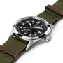 The Hamilton x Call of Duty Black Ops 7, a Swiss-made watch by Hamilton, features a black dial and green fabric strap with brown leather accents, shown angled on a white background.